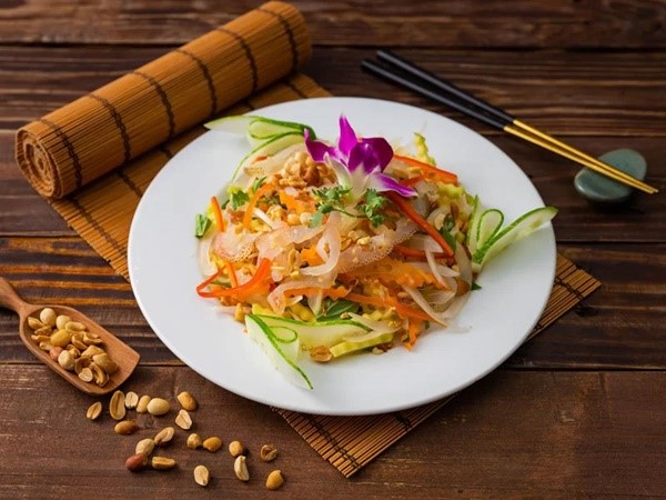 Một đĩa gỏi sứa được bày trên nền bàn gỗ, gợi lên không khí bình dị của miền biển Việt Nam.