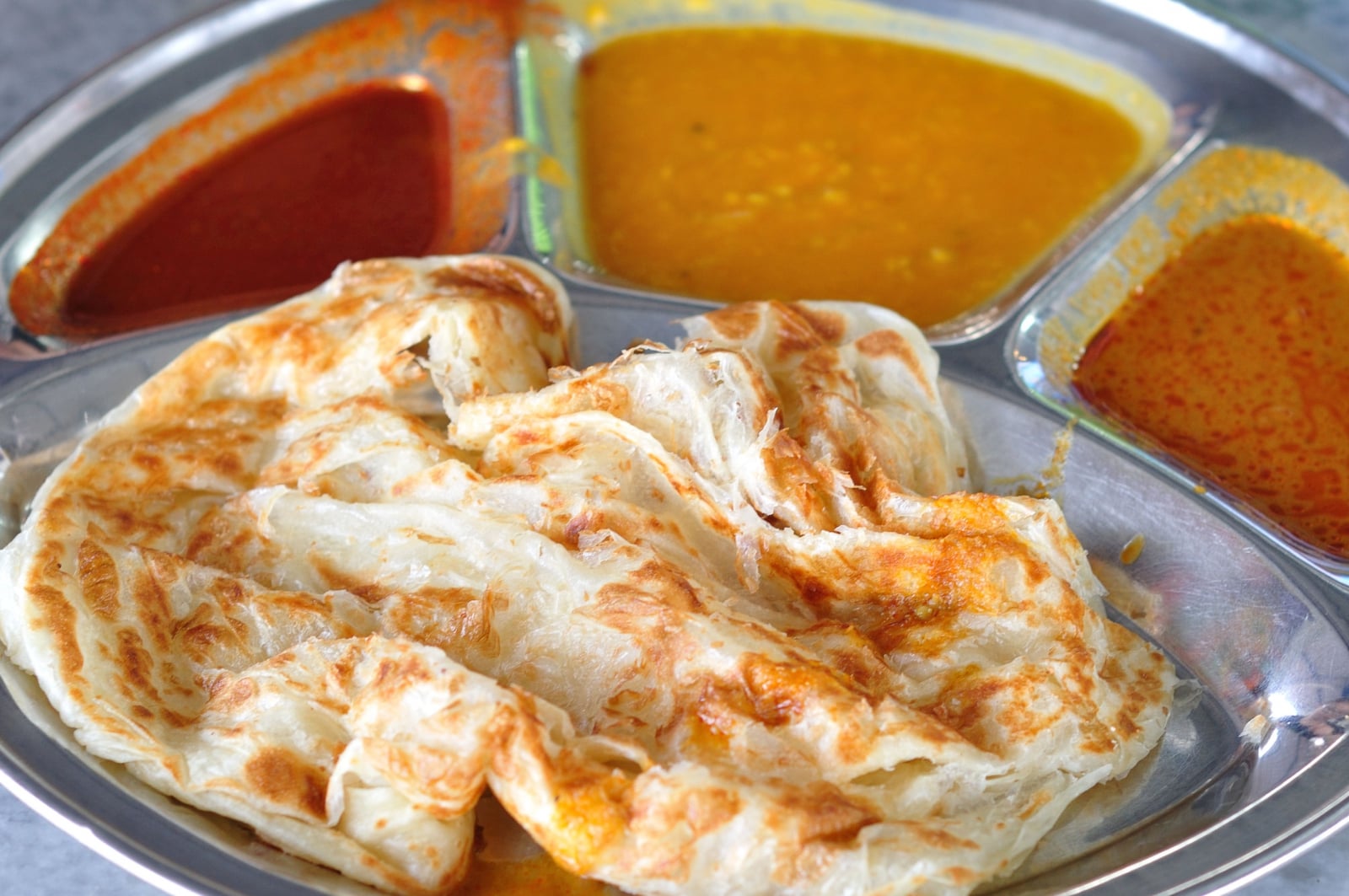 Roti Canai là món bánh mì dẹt chiên giòn, ăn kèm cà ri hấp dẫn